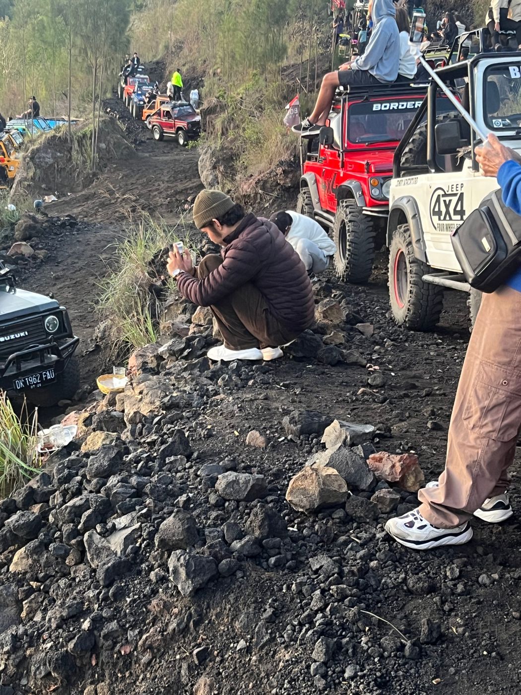 A man resting in a deep squat on a volcanic hillside in Bali